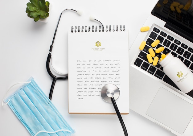 Stethoscope and notebook with laptop beside