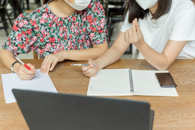 Zdjęcie biznesowe kobiety z medyczną maską pracuje wpólnie