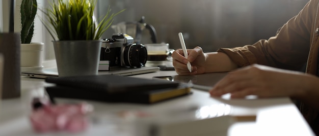 Zdjęcie fotograf kobieta pracuje z makietą tabletu na stole z aparatem i dostawami w studio