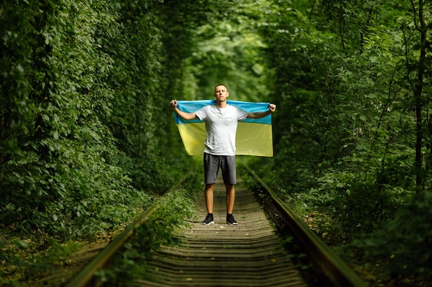 Mężczyzna podniósł ręce i trzyma ukraińską flagę za plecami koncepcja ukraińskiego patriotycznego wiecu poparcia dla Ukrainy