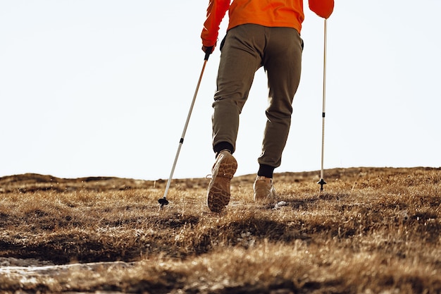 Zdjęcie mężczyzna podróżujący z kijami trekkingowymi w górę