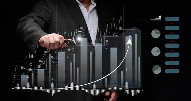 mężczyzna w czarnej koszuli stoi przed holograficznym wykresem z rosnącymi wskaźnikami. Wzrost biznesu, wzrost sprzedaży. Wysoka wydajność