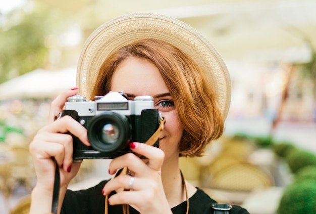 Młoda kobieta hipster trzymając w rękach retro aparat i robienie zdjęć