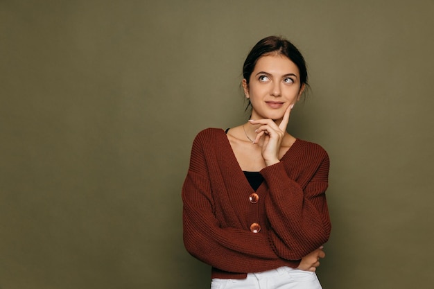 Młoda krótkowłosa brunetka myśląca patrząc na lewą stronę miejsca na kopię podtrzymującą jej podbródek