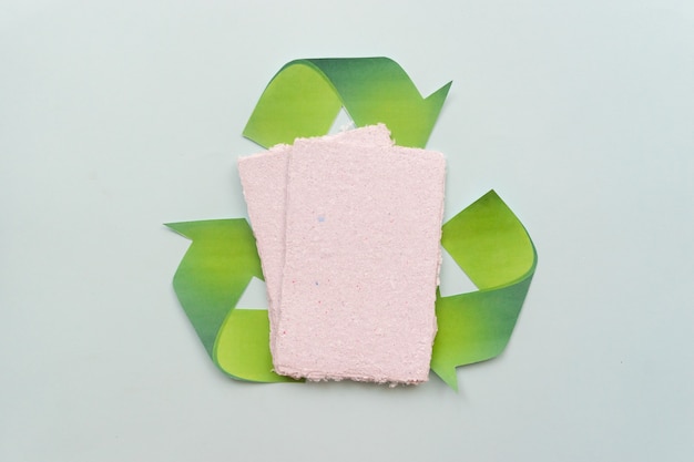 Na stole leżą kartki papieru i znak „zero waste”. Koncepcja recyklingu papieru.