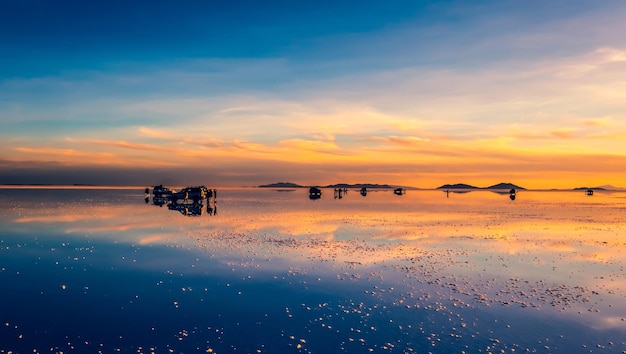 Niesamowita sceneria lustrzana salar de uyuni z turystami i samochodami