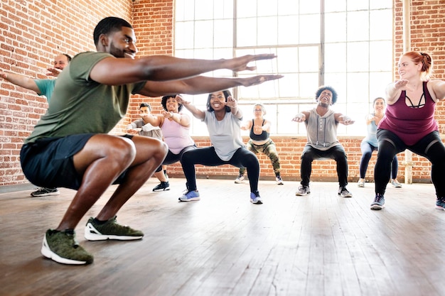 Osoby wykonujące przysiady na zajęciach fitness