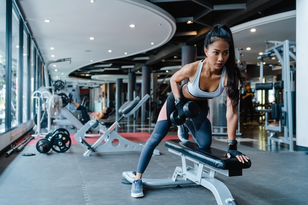 Piękna młoda azjatycka dama robi podnoszenie treningu spalania tłuszczu ze sztangą w zajęciach fitness.