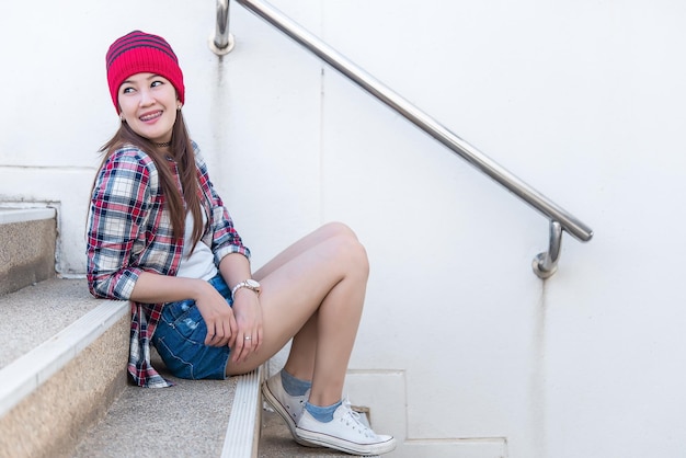 Zdjęcie portret pięknej azjatyckiej hipster dziewczyny na tle schodówstyl życia współczesnej kobietytajlandia szczęśliwa kobieta weź koncepcję fotograficzną