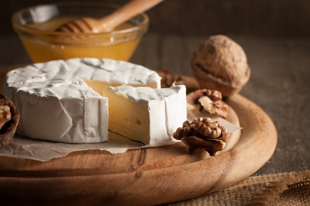 Ser camembert i brie na drewnianym z pomidorami, sałatą i czosnkiem. Włoskie jedzenie. Nabiał.