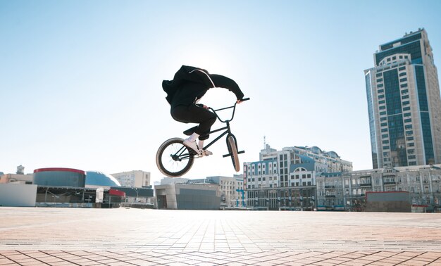 Zdjęcie sylwetka jeźdźca bmx skoki w krajobrazie miejskim w jasny letni dzień