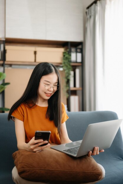 Zdjęcie uczennice z biblioteki azjatyckich dziewcząt siedzące na kanapie używające laptopa i tabletu do wyszukiwania informacji w internecie