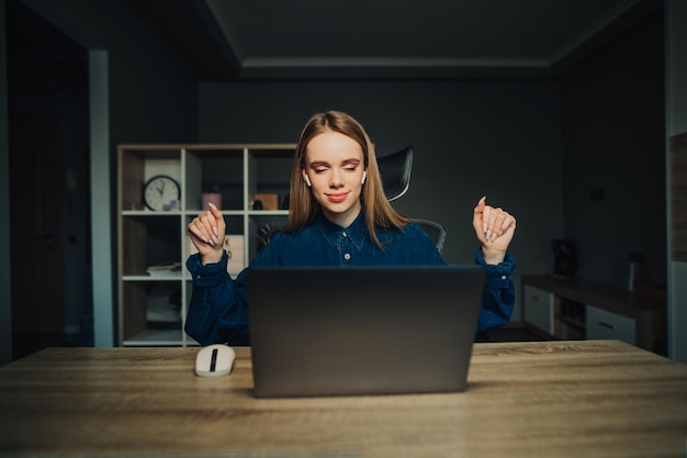 Wesoła freelancerka pracująca w domu przy stole i tańcząca