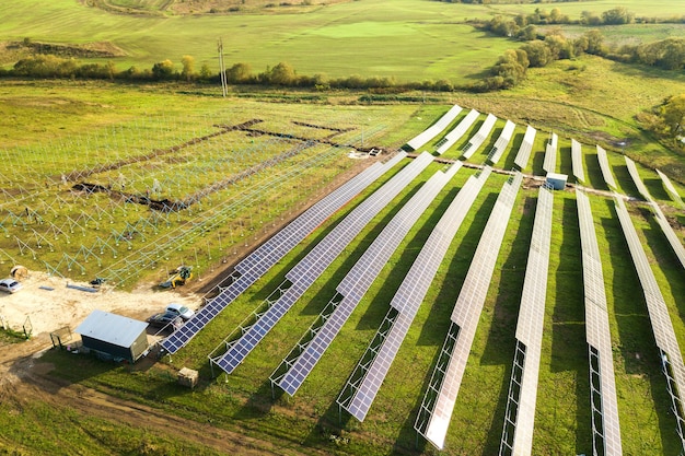 Widok z lotu ptaka elektrowni słonecznej w budowie na zielonym polu. Montaż paneli elektrycznych do produkcji czystej energii ekologicznej.