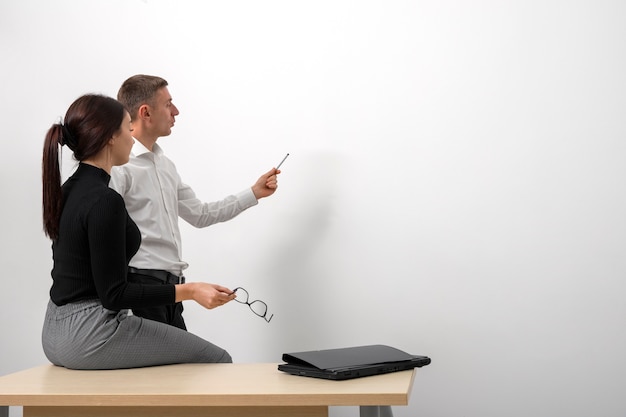 Geschäftsmitarbeiter, die Statistiken auf einer weißen Tafel im Büro präsentieren