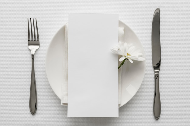 Mise à plat de la maquette du menu de printemps sur une assiette avec des couverts et des fleurs