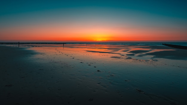 Gratis foto adembenemend uitzicht op de weerspiegeling van de zonsondergang in de oceaan in domburg, nederland