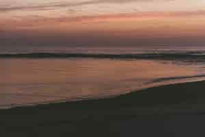 Gratis foto betoverend uitzicht op de oceaan en het strand tijdens zonsondergang