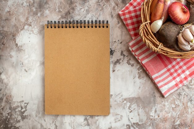 Bovenaanzicht mand met groenten, knoflook, uien en bieten op lichte foto rijpe dieetkleurensalade