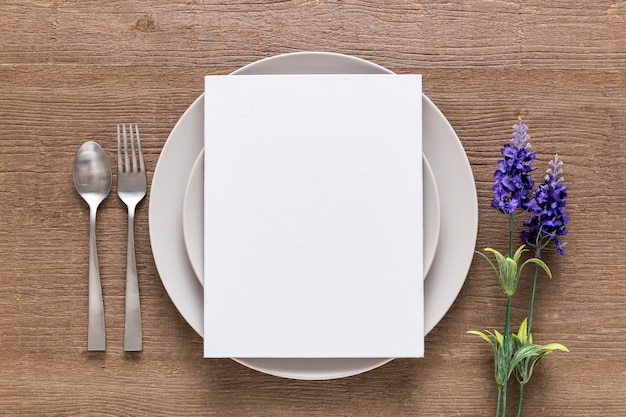 Bovenaanzicht van blanco menu papier op plaat met bloemen en bestek