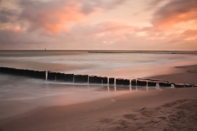 Gratis foto golfbreker in het zandstrand tijdens de zonsondergang