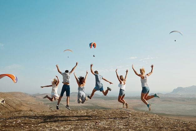 Gratis foto groep vrienden die bovenop heuvel springen