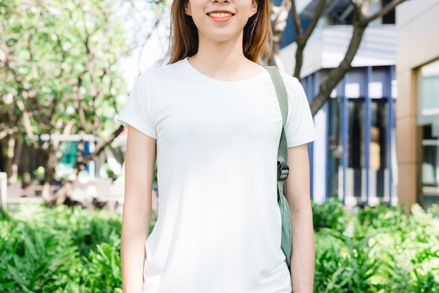 Gratis Foto het aziatische lange bruine haar van het hipstermeisje in witte lege t-shirt bevindt zich in het midden van straat. een fem