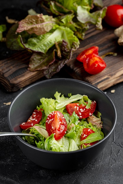 Hoge hoek verse groene salade met tomaten in donkere kom