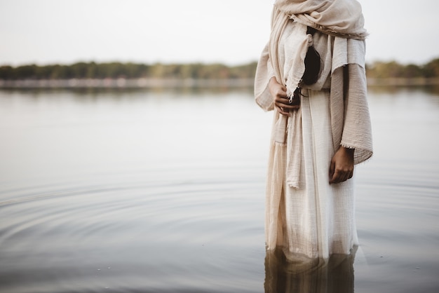 Gratis Foto mooie foto van een vrouw die een bijbels gewaad draagt terwijl ze in het water staat