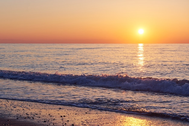 Gratis foto mooie kleurrijke zonsondergang over de zee en de zon schijnt. oranje lucht.