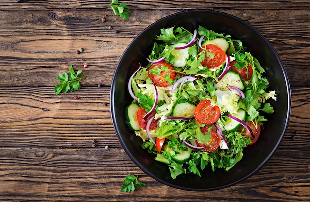 Gratis foto salade van tomaten, komkommer, rode uien en slabladeren. gezond zomervitaminemenu. veganistisch plantaardig voedsel. vegetarische eettafel. bovenaanzicht plat leggen