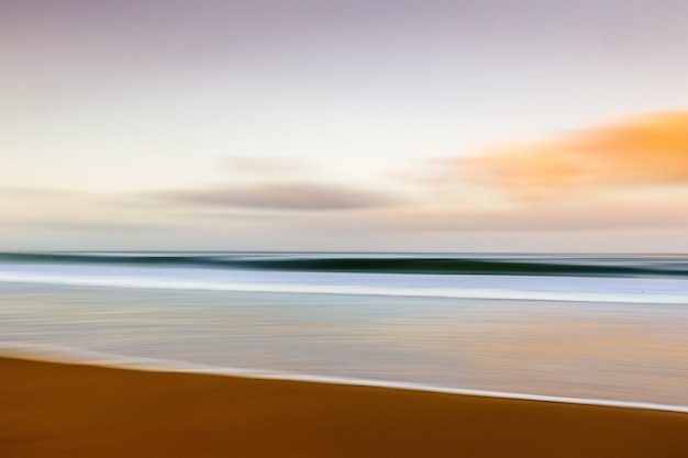 Gratis foto strand tijdens de zonsondergang met een bewegingseffect