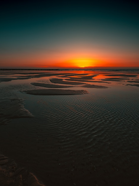 Gratis foto weerspiegeling van de zonsondergang in de oceaan gevangen in domburg, nederland