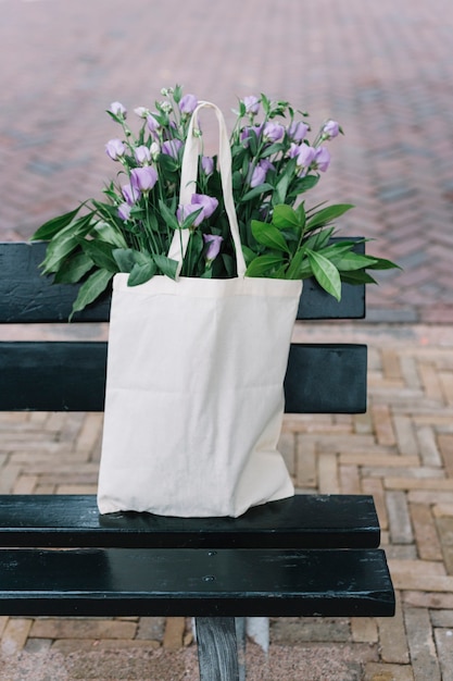 Gratis Foto witte katoenen handtas met prachtige paarse eustoma bloemen in de zwarte bank