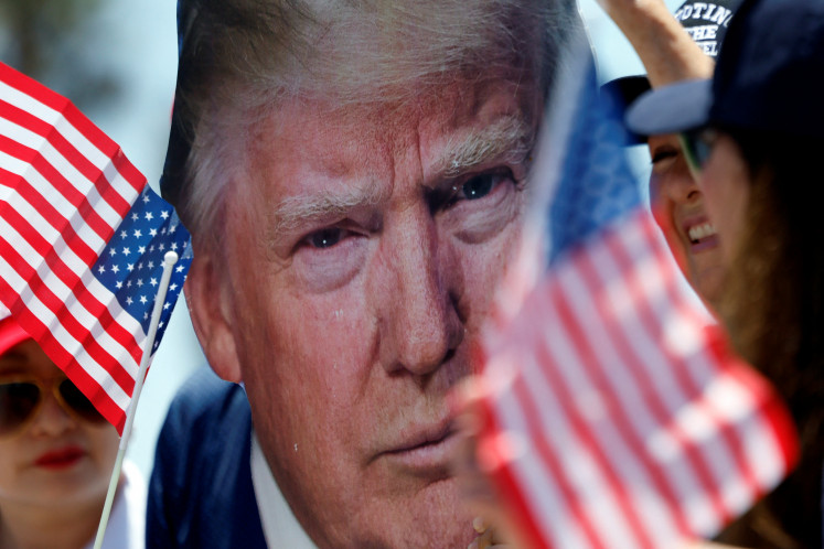 A pro-Trump supporter holds a portrait of former US President Donald Trump during a demonstration a day after Trump was shot in an assassination attempt during a rally in Pennsylvania, in Huntington Beach, California, US.July 14, 2024. 