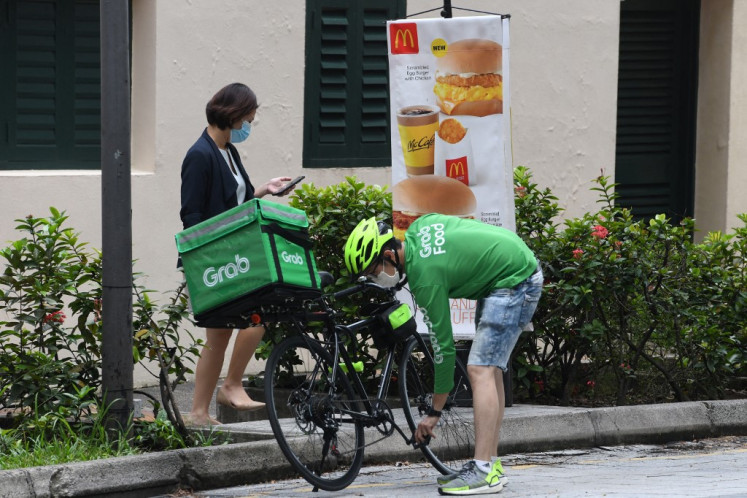 A Grab food delivery rider checks his bicycle outside a fast food chain in Singapore on Sept. 30, 2020.