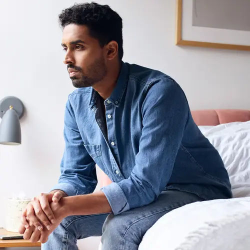 photo of man sitting on bed