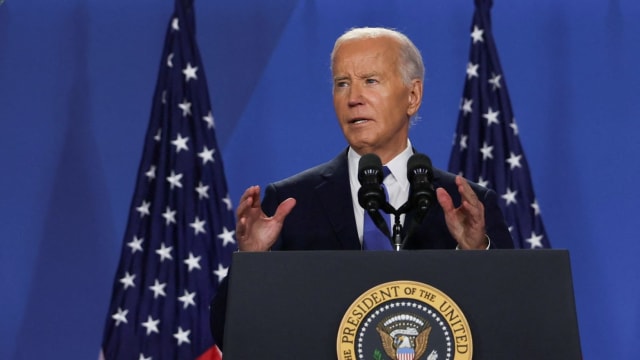 Joe Biden gesticulates behind a lectern with the presidential seal