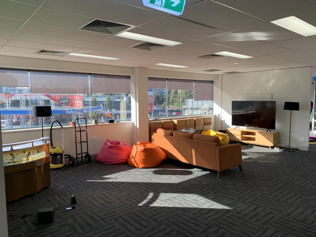 An empty breakout area of an office with a large TV and sofa