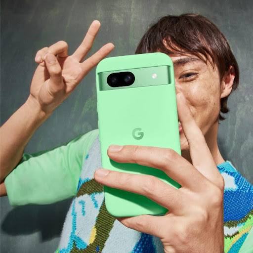 A person poses for a selfie with their Pixel 8a in the colour Aloe.