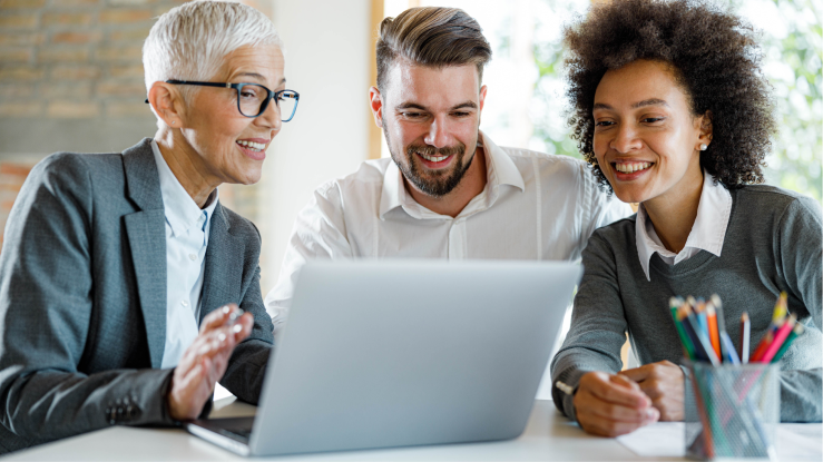 Tres personas hablan sobre una presentación de ventas en una laptop.