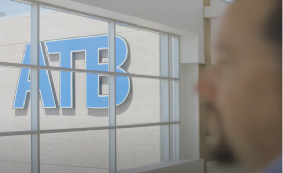 Logo des ATB auf einem Gebäude mit einem Mann, der nach außen blickt