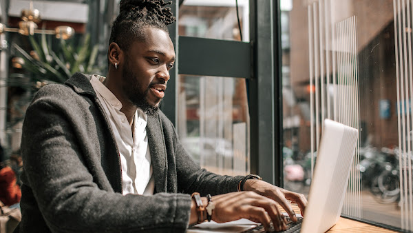 Un hombre usando un traje y trabajando en una laptop