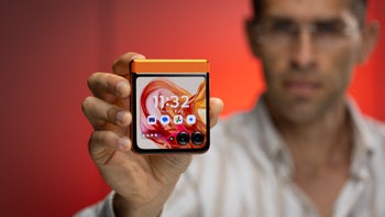 Close-up of a man holding a folded Motorola Razr (2024) in Spritz Orange, with the cover screen turned on.