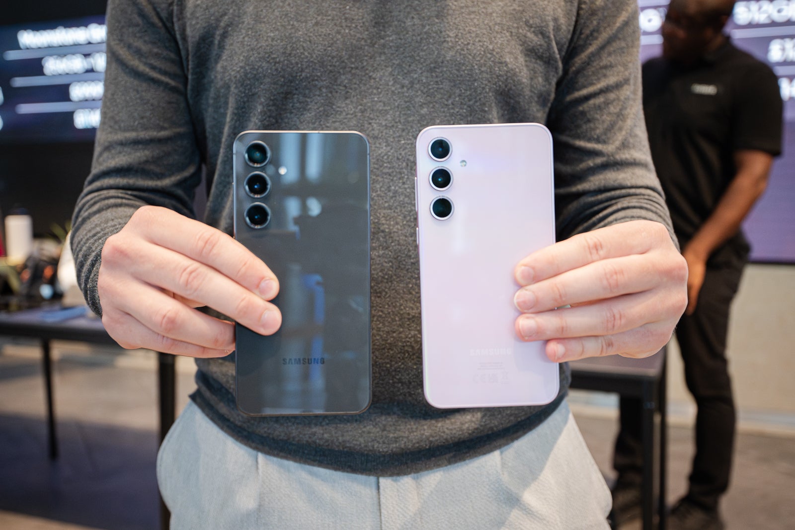 A person holding the S24 FE and S23 FE with their backs facing the camera.