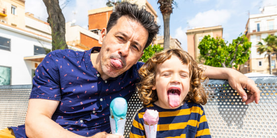 Happy father and son sitting on bench enjoying an ice cream