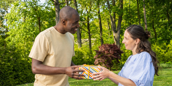 Woman giving a gift to her husband outdoors