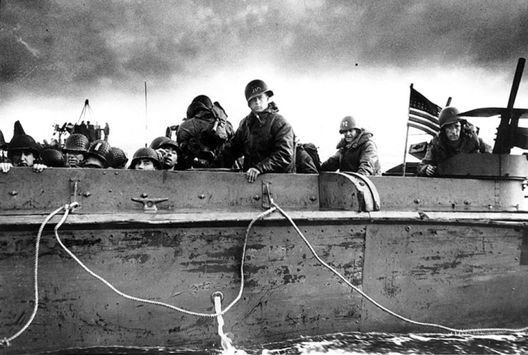 Troops on a landing craft approach a Normandy beach.