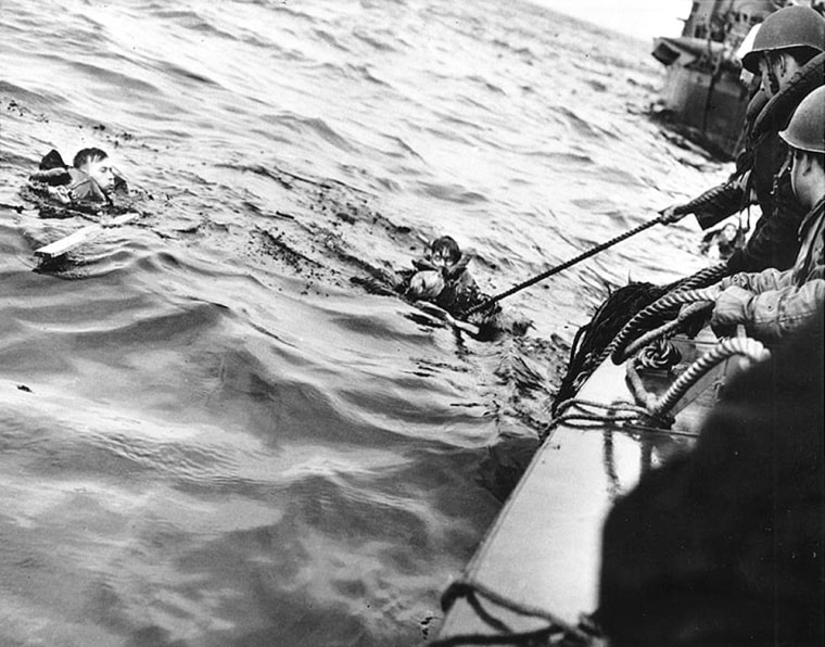 Coast Guardsmen rescue two survivors after their vessel was hit off Normandy on June 6, 1944.