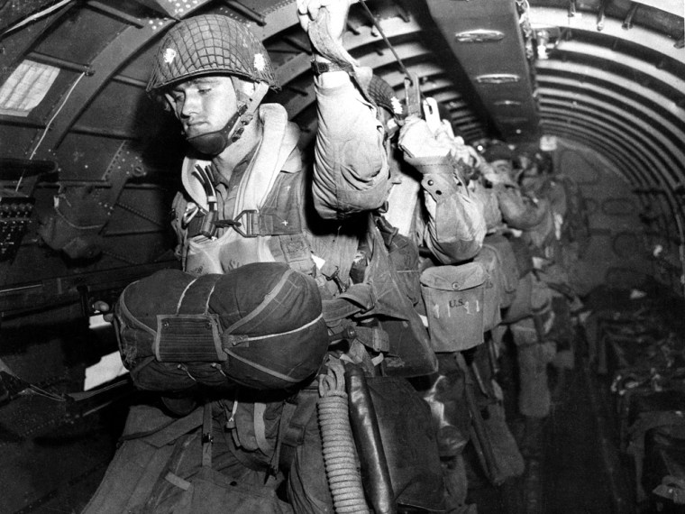 U.S. paratroopers fix their static lines ahead of a pre-dawn jump over Normandy on D-Day.
The parachute troops were assigned one of the most difficult tasks of the initial operation -- a night jump behind enemy lines five hours before the coastal landings.
The decision to launch the airborne attack in darkness instead of waiting for first light is controversial to this day.